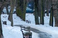 Park benches covered in snow aligned on a sidewalk Royalty Free Stock Photo