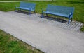 Park benches in light blue made of metal strips similar to a lattice. trash can and beautiful lawn with park paths of gravel thres