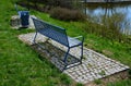 Park benches in light blue made of metal strips similar to a lattice. trash can and beautiful lawn with park paths of gravel thres