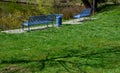 Park benches in light blue made of metal strips similar to a lattice. trash can and beautiful lawn with park paths of gravel thres