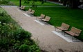 Park benches lined with wood along the entire wide threshing gravel beige path, lawns, flower lush, perennial flower beds blooming