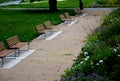 Park benches lined with wood along the entire wide threshing gravel beige path, lawns, flower lush, perennial flower beds blooming