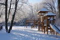 A park covered in snow with a play structure standing in the center as children play and make snowmen, A playground in a winter Royalty Free Stock Photo