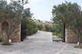 Park entry with open wrought-iron gate in gradient back and shut off the track Royalty Free Stock Photo