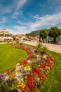 Park with flowerbed and Wolfgangsee lake promenade full of tourists on a sunny summer day in austrian village St.Gilgen
