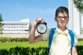 In the park, in the fresh air, close-up, the student holds an alarm clock in his hands and smiles that it is noon