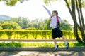 In the park, in the fresh air, a schoolgirl is having fun and jumping up, raising her hand Royalty Free Stock Photo