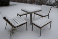 Park furniture chess table and chairs for four people made of light metal and wooden beams with backrest. on a bright snowy plain Royalty Free Stock Photo