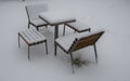 Park furniture chess table and chairs for four people made of light metal and wooden beams with backrest. on a bright snowy plain Royalty Free Stock Photo