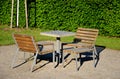 Park furniture chess table and chairs for four persons made of light metal and wooden beams with backrest on bright glade area gra Royalty Free Stock Photo