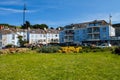 Park in Howth, Ireland with light blue buildings, people and cars with a blue sky in the background