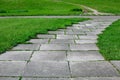 Park path made of square tiles overgrown with grass in a parkland. Royalty Free Stock Photo