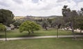 Park with Paved Walkway and Trees with a Hillside and Clouds in the Background