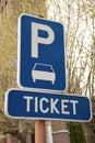 Park sign with a ticket text sign on the road surrounded by trees under the sunlight