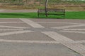 Park space with paved pavement with lines and patterns. In the background is a bench and a lawn with a green lawn Royalty Free Stock Photo