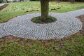 In the park there is a path surrounding a tree growing directly in the compositional axis of the historic garden. The cobblestones Royalty Free Stock Photo