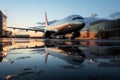 Parked aircraft by the jetway, mirrored in a puddle\'s shimmering reflection Royalty Free Stock Photo