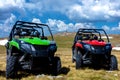 Parked ATV and UTV, buggies on mountain peak with clouds and blue sky in background