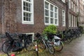 Parked bicycles by the wall near a brick house on a rainy day. Eco transport tradition in Amsterdam