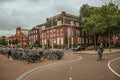 Parked bicycles and woman pedaling in street with cloudy sky in Amsterdam. Royalty Free Stock Photo