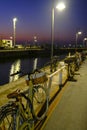 Parked bikes in the harbor of Senigallia, Italy at night. Lights, street lamps, and water reflecting in the city Royalty Free Stock Photo