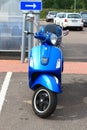 Parked blue scooter in the daytime. Front view