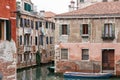 Parked boats on a narrow Venetian canal with turn.