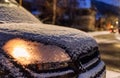 Parked car with light on covered by snow at night Royalty Free Stock Photo