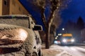 Parked car with light on covered by snow at night Royalty Free Stock Photo