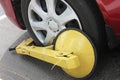 A parked car with a yellow tire lock for the illegal parking violation. Wheel lock-in restricted area for parking. Royalty Free Stock Photo