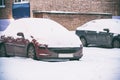 Parked cars covered with snow.