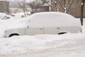 Parked cars, covered in snow, stand along the road. Snowfall in the city, falling snowflakes. Concept: traffic collapse, increased