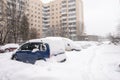 Parked cars, covered in snow, stand along the road. Snowfall in the city, falling snowflakes. Concept: traffic collapse, increased