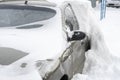 Parked cars, covered in snow, stand along the road. Snowfall in the city, falling snowflakes. Concept: traffic collapse, increased