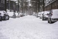 Parked cars covered with snow in the street in a neighbourhood. Suburban urban city street scene Royalty Free Stock Photo