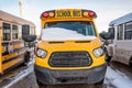 Parked front end of a school bus with the windshield covered with snow after a storm Royalty Free Stock Photo
