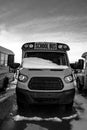 Parked front end of a school bus with the windshield covered with snow after a storm Royalty Free Stock Photo