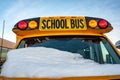 Parked front end of a school bus with the windshield covered with snow after a storm Royalty Free Stock Photo