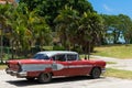 Parked red vintage car in Havana Cuba near the beach Royalty Free Stock Photo