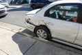 Parked white car with body damage from an accident