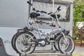 A parked white motorhome with a cycle carrier attached to the rear, with two bicycles