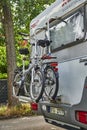 A parked white motorhome with a cycle carrier attached to the rear, with two bicycles