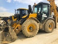 Parked yellow backhoe loader. Earthmoving, excavating, digging machinery at construction site Royalty Free Stock Photo