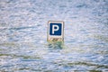 Parking cars road sign partially submerged in a flood.