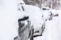 Parking cars after snowfall. Automobiles covered with snow. Winter concept