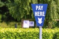 Parking charge pay here blue sign post in green environment Royalty Free Stock Photo