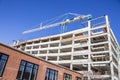 Parking garage under construction - slanted view of concrete bones of building with giant crane on top with lower pre-existing