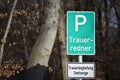 A parking lot sign at the forest in German with the words: bereavement speaker and a white sign with the words: bereavement counse Royalty Free Stock Photo