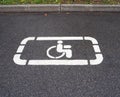 Parking lot with white painted handicapped symbol of wheelchair on asphalt, parking spaces for disabled visitors Royalty Free Stock Photo