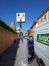 Parking meter and parked vehicles on a narrow medieval street in Pisa, Italy